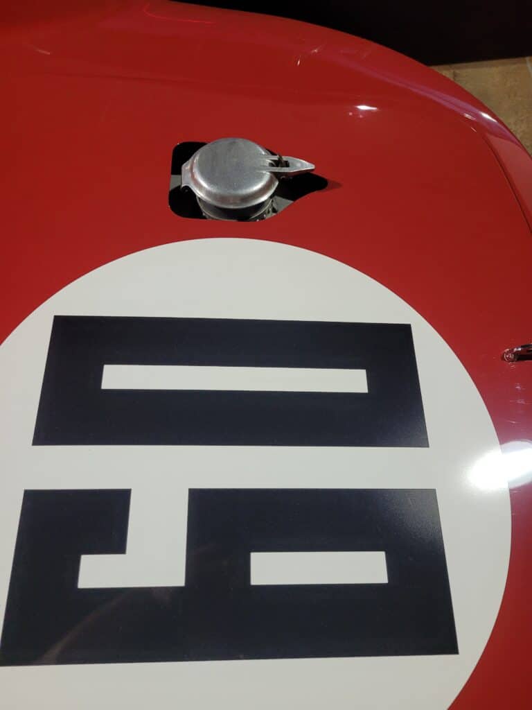A red Maserati Birdcage racing car in a museum filler cap