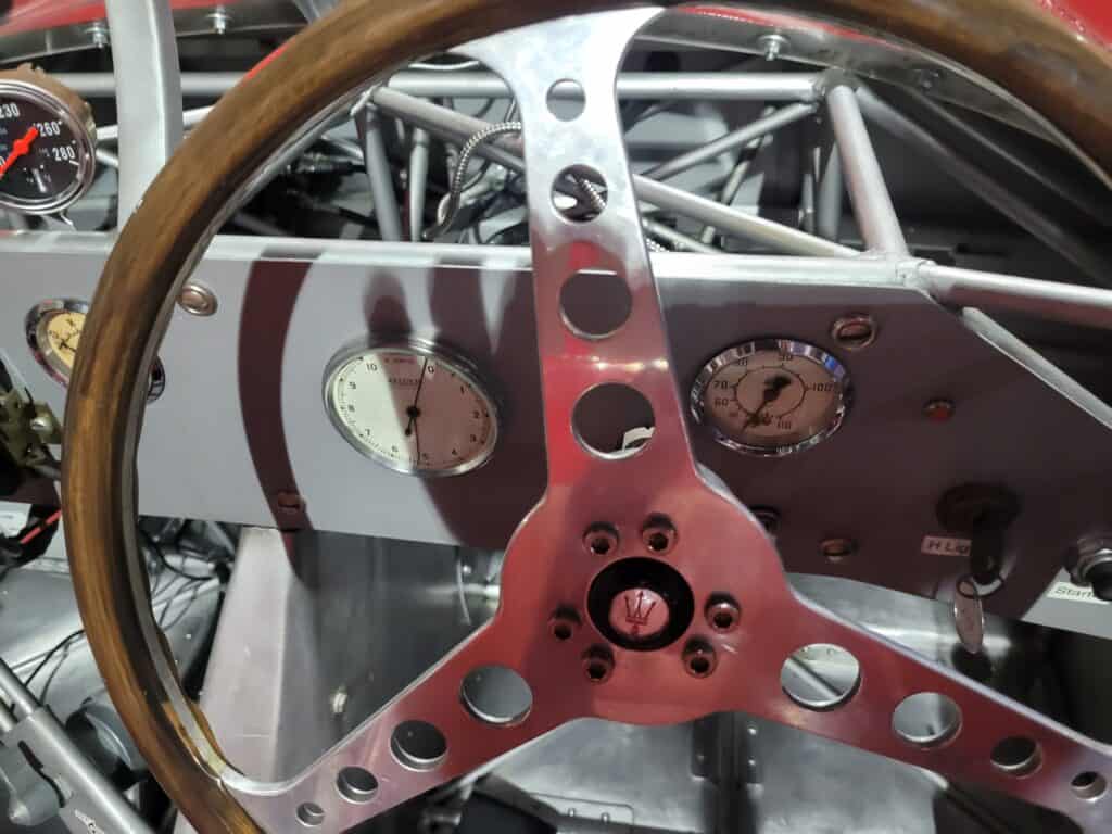 A red Maserati Birdcage racing car steering wheel in a museum